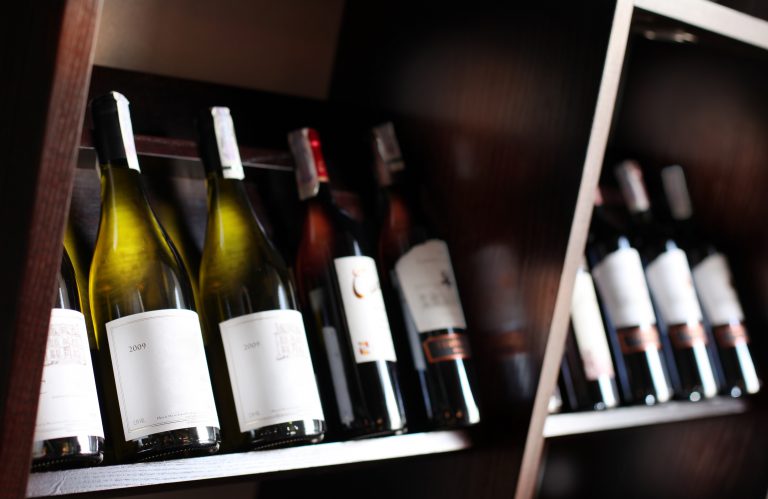 Wine bottles on a wooden shelf.